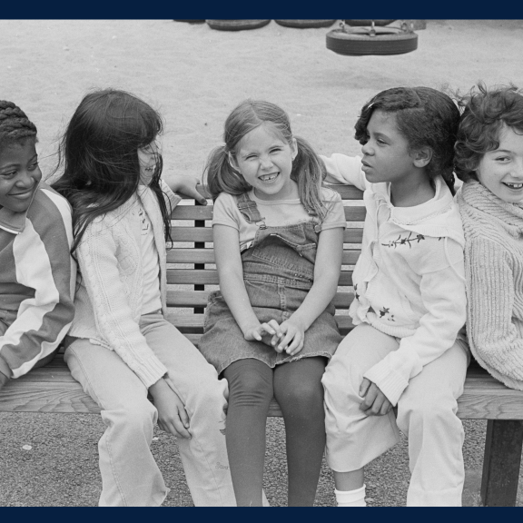 Black and white photo of children sitting on a bench