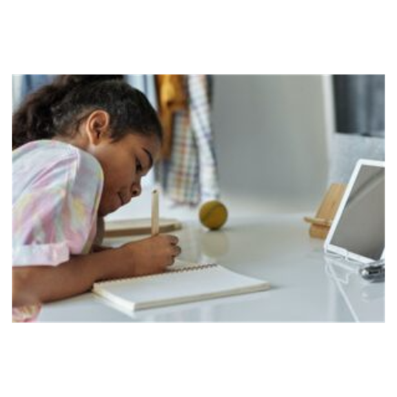 Child writing in a notebook at a desk in a bedroom