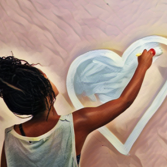 Picture of young person from behind painting a heart on a wall
