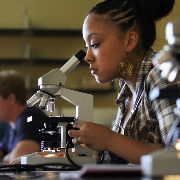 Female biology student looking into a microscope