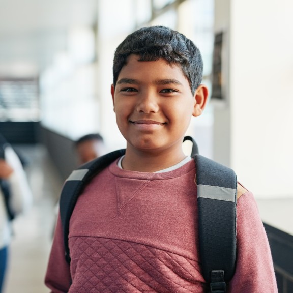 Smiling Student wearing backpack in school hallway