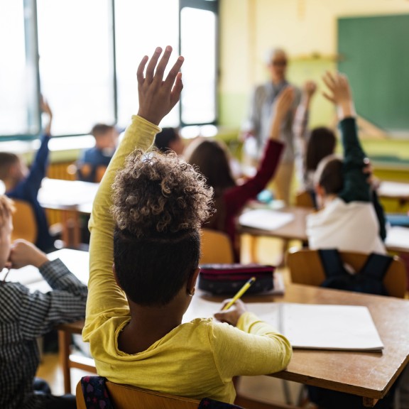Children raising hands in class