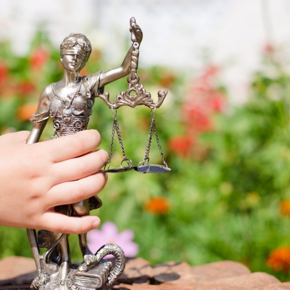 Child holding sculpture of Themis with scales of justice