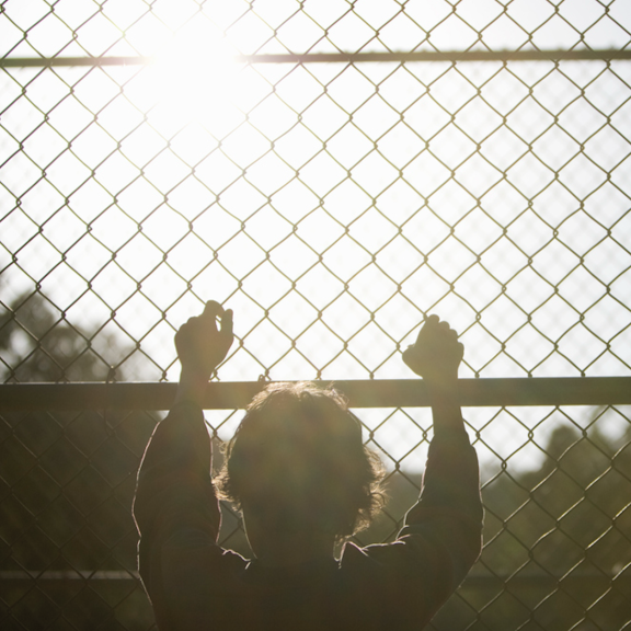 Young person standing at a barrier fence