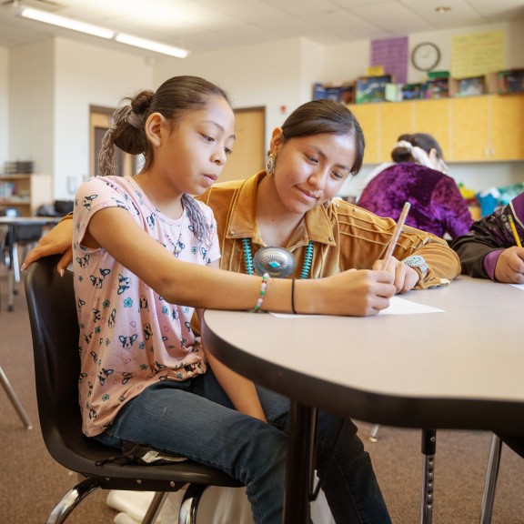 A student is helped by a teacher in class