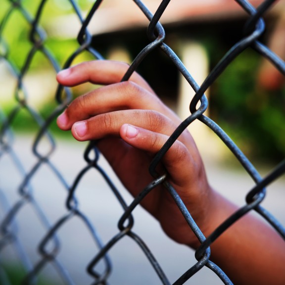 Girl's hand on fence while detained