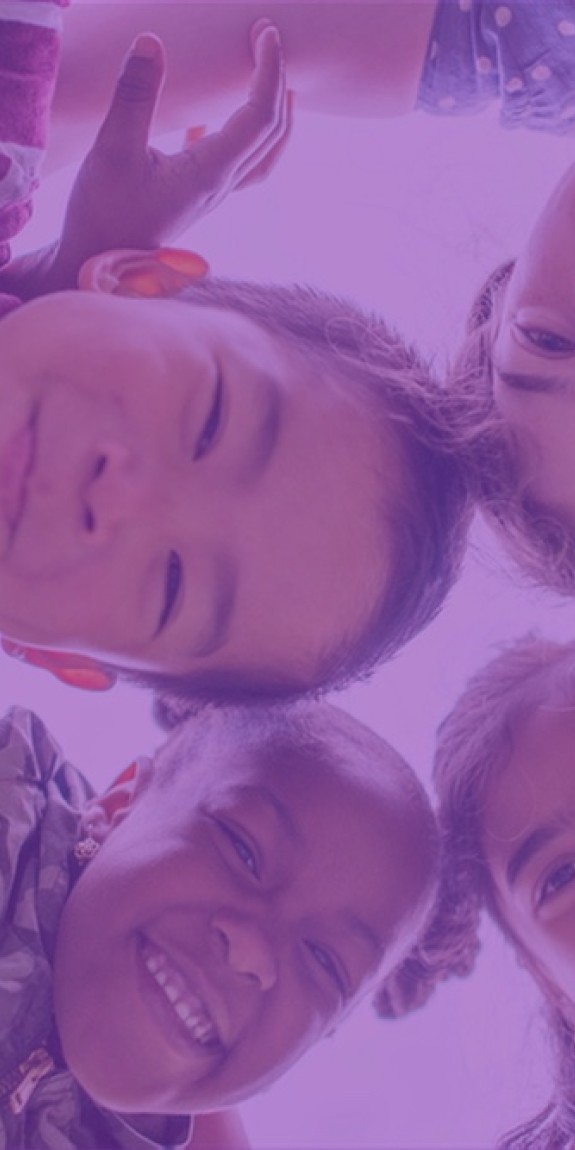 Circle of children look down at the camera