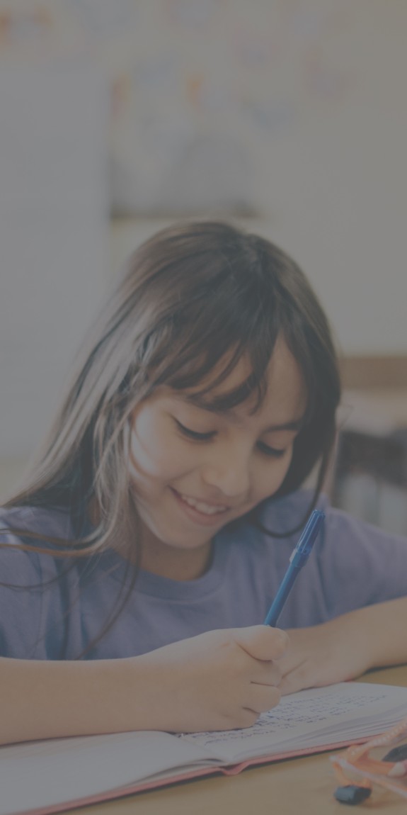 student sits at a desk writing in a booklet