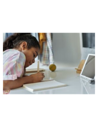 Child writing in a notebook at a desk in a bedroom