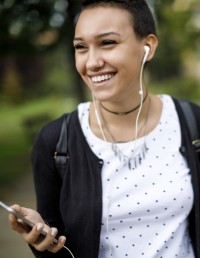 Young person outside smiling. Wearing headphones