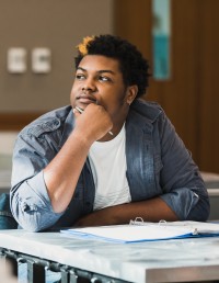 student sits thoughtfully at a desk