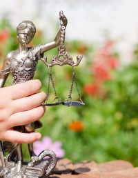 Child holding sculpture of Themis with scales of justice