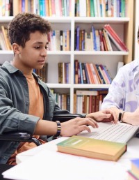 Student in a wheelchair uses laptop in library