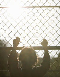 Young person standing at a barrier fence