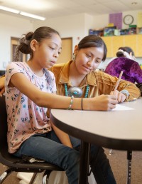 A student is helped by a teacher in class