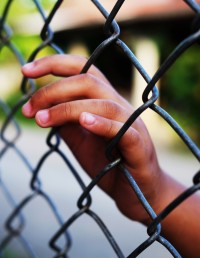 Girl's hand on fence while detained