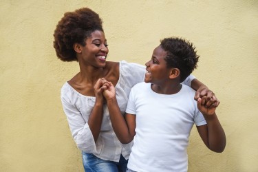 Adult and child smile at each other holding hands