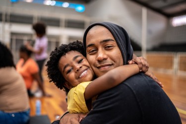Child has arms around adult neck in a hug