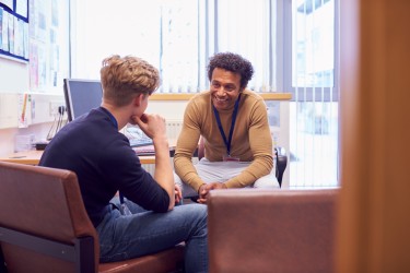 Student and adult sit in an office talking